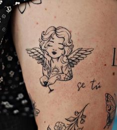 a woman with tattoos on her leg and arm is looking down at the ground while she has an angel tattoo on her thigh