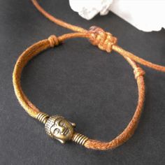 Light brown cord bracelet with a bronze tone Buddha head charm and wire binding. It is fully adjustable in size using a hand tied macramé flat knot. ⭐Free local and international shipping⭐ Buddha Bracelets, Buddha Head, Wire Binding, Cord Bracelet, Cord Bracelets, Charm Bracelets, Bracelet Making, Bracelets For Men, Rope Bracelet