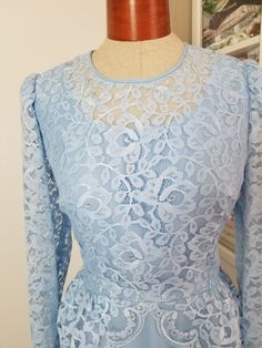 "Pretty dress in an icy periwinkle shade of blue. The top has a layer of lace in a peplum style that is longer in the back. The lace is adorned with tiny pearls and prong set rhinestones. This dress has long sleeves and zips up the back. Hook and eye at top of zipper. Has belt loops and no belt. Has some 40's vibes! Label reads, \"The Bridal Shoppe of Columbus Ohio\". Was probably a mother of the bride dress. This is in good condition, except for it needs a few stitched on the zipper (see photo) Peplum Styles, Mother Of The Bride Dress, Ice Queen, Pretty Dress, Columbus Ohio, Mother Of The Bride Dresses, Blue Lace, Ice Blue, Formal Dress