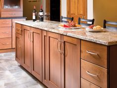 a large kitchen with wooden cabinets and marble counter tops, along with two wine bottles on the island