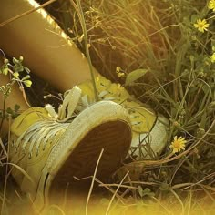 an old pair of yellow tennis shoes sitting in the grass with daisies around them