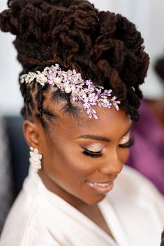 a woman wearing a white shirt and purple flowers in her hair