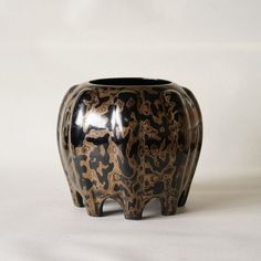 a black and brown vase sitting on top of a white table