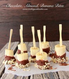 chocolate, almond and banana bites are arranged on a piece of parchment paper with toothpicks sticking out of them