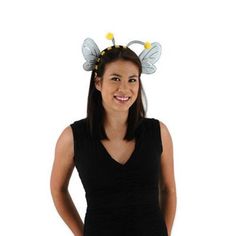 a woman wearing a bee headband and black dress standing in front of a white background