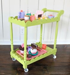 a green cart filled with lots of small items on top of a wooden floor next to a wall