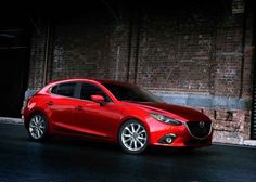 a red mazda car parked in front of a brick building