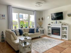 a living room filled with furniture and a flat screen tv mounted on the wall above a fire place