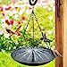 a bird feeder hanging from the side of a wooden pole in front of a flower garden