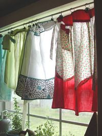 several different colored curtains hanging on a window sill next to a potted plant