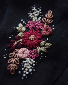 an embroidered flower on a black shirt with pearls and bead work in the center