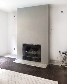 an empty living room with a fireplace in the middle