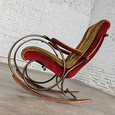 an old fashioned rocking chair with red and gold fabric