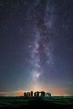 the milky over stonehenge at night with stars in the sky and green grass