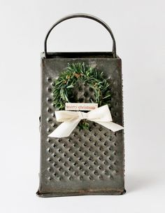 an old metal box with a wreath on it and a ribbon tied around the handle