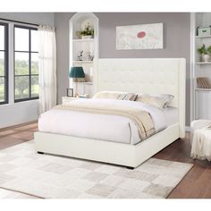 a white bed sitting in a bedroom on top of a hard wood floor next to a window