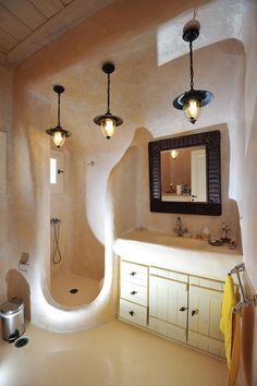 a bathroom with an oval shaped shower and sink area, along with two lights hanging from the ceiling