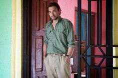 a man standing in front of a door wearing khaki pants and a green shirt