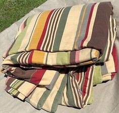 three blankets folded on top of each other in the grass next to an open umbrella