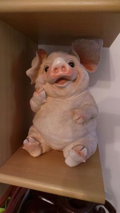 a stuffed pig sitting on top of a wooden shelf