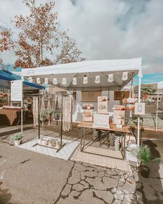 a white tent set up with tables and chairs in front of it, surrounded by other tents