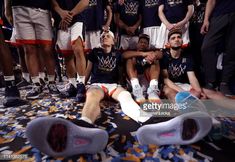 a group of basketball players sitting on the floor with their feet up in front of them