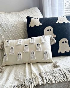 two pillows with ghost faces on them sitting on a couch