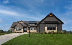 a large gray house sitting on the side of a lush green field in front of a blue sky