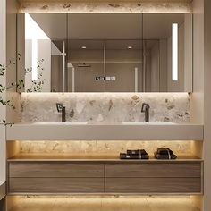 a bathroom with two sinks, mirrors and lights on the wall above it is illuminated by recessed lighting