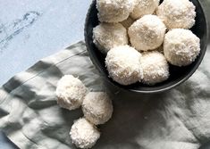 a black bowl filled with sugar covered donuts on top of a white cloth next to a napkin