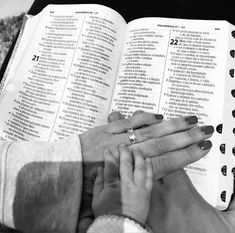 two people holding hands over an open book