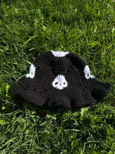 a black and white crocheted hat laying in the grass