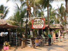 a man standing in front of a store on the side of a road next to palm trees