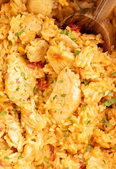 a close up of food in a pan with a wooden spoon