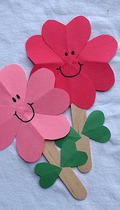 three paper flowers with faces drawn on them