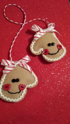 two ornaments are hanging on a red tablecloth with white and red ribbon around them