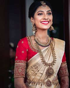 a woman in a red and gold sari smiles at the camera while wearing jewelry