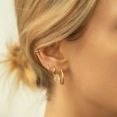 a close up of a person wearing gold earring with small stars on the side