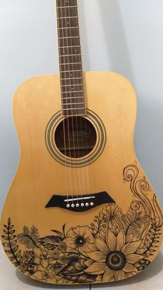 an acoustic guitar with flowers painted on it