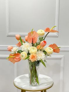 a glass vase filled with white and orange flowers