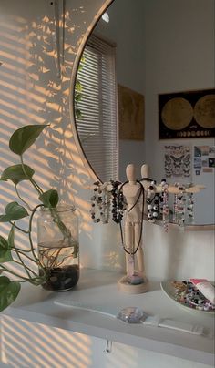 a mirror sitting on top of a white shelf next to a plant