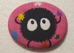 a painted rock with an image of a black sheep on it's face and flowers around its eyes