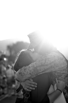 a man and woman hugging each other in front of the sun with their arms around each other