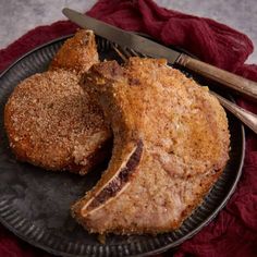 two pieces of meat on a plate with a knife and fork next to it, ready to be eaten