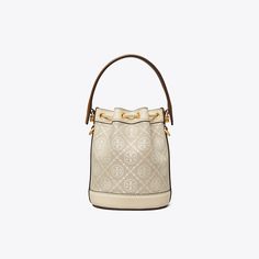 T Monogram is a classic pattern inspired by traditional Pennsylvania Dutch quilting. Meticulously crafted in woven jacquard, the collection speaks to the timelessness of great style.The mini bucket bag closes with drawstrings, secured by our gold Double T cord stopper. Worn crossbody, the top handle falls naturally. Every detail is considered, with special attention to function and versatility. T Monogram, Mini Bucket Bag, Miller Sandal, Graphic Design Elements, Pennsylvania Dutch, Mini Bucket Bags, Barrel Bag, Mini Bucket, Womens Designer Handbags