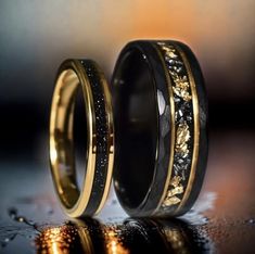 two wedding rings with black and gold glitters on the inside, one has a diamond in it