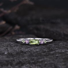 a three stone ring with amethyst stones on it's sides, sitting on top of a rock