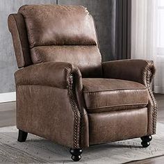 a brown recliner chair sitting on top of a rug in front of a window