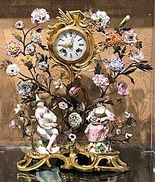 an ornate clock with flowers and figurines on it