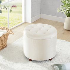 a white ottoman sitting on top of a rug next to a window